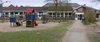 Außenbereich der Kita Schuby mit Spielturm und Sandkiste. Im Hintergrund der Eingangsbereich. 